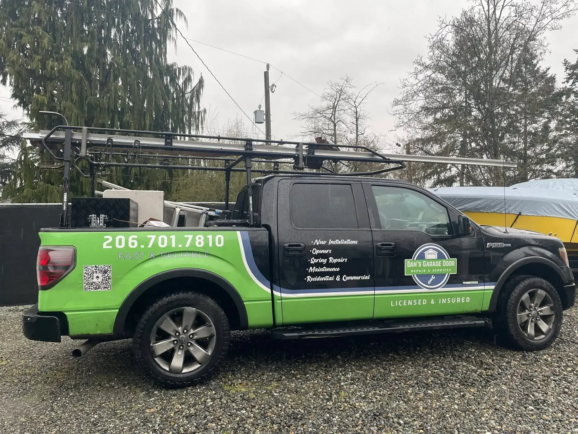 Green and black Dan's Garage Door Repair Services truck with ladder rack