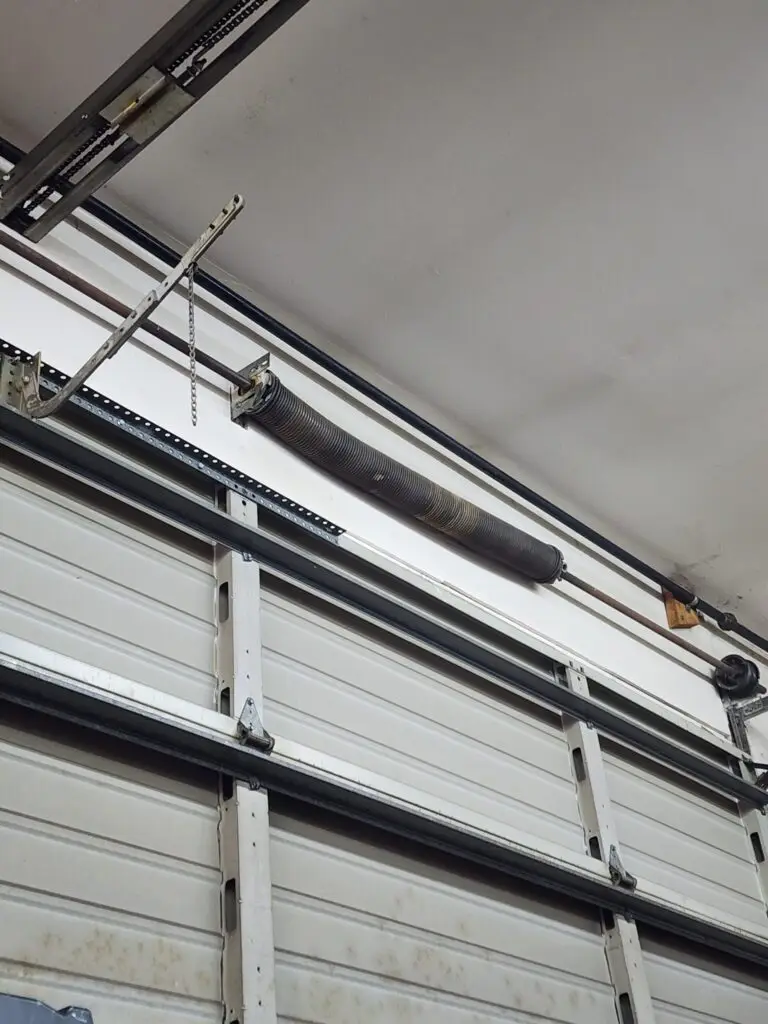 Garage door torsion spring system with metal tracks and safety cable.