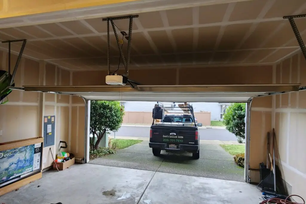 Interior view of a garage with an open door, showing a parked truck from Dan's Garage Door service outside.