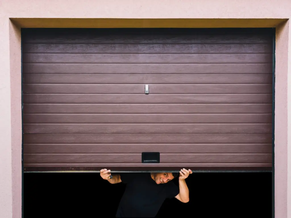 Man peeking through a partially opened garage door.