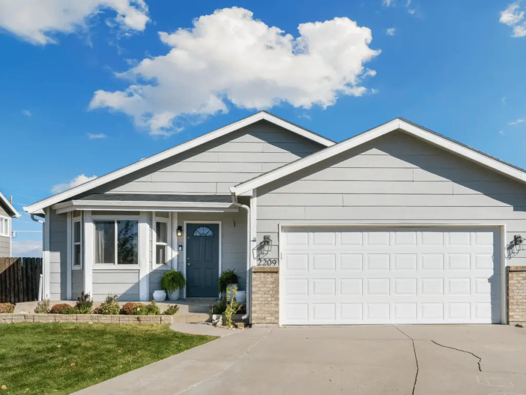 Suburban home with a prominent garage door under a clear sky.