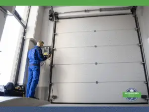 Technician servicing a garage door control panel in a workshop.
