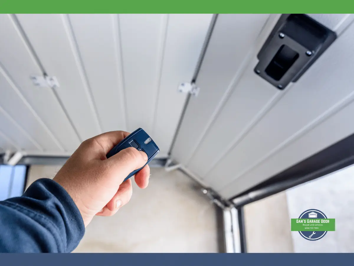 Hand holding blue garage door remote under garage door opener