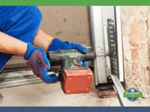 Person installing a garage door track, using a drill on the guide rail.