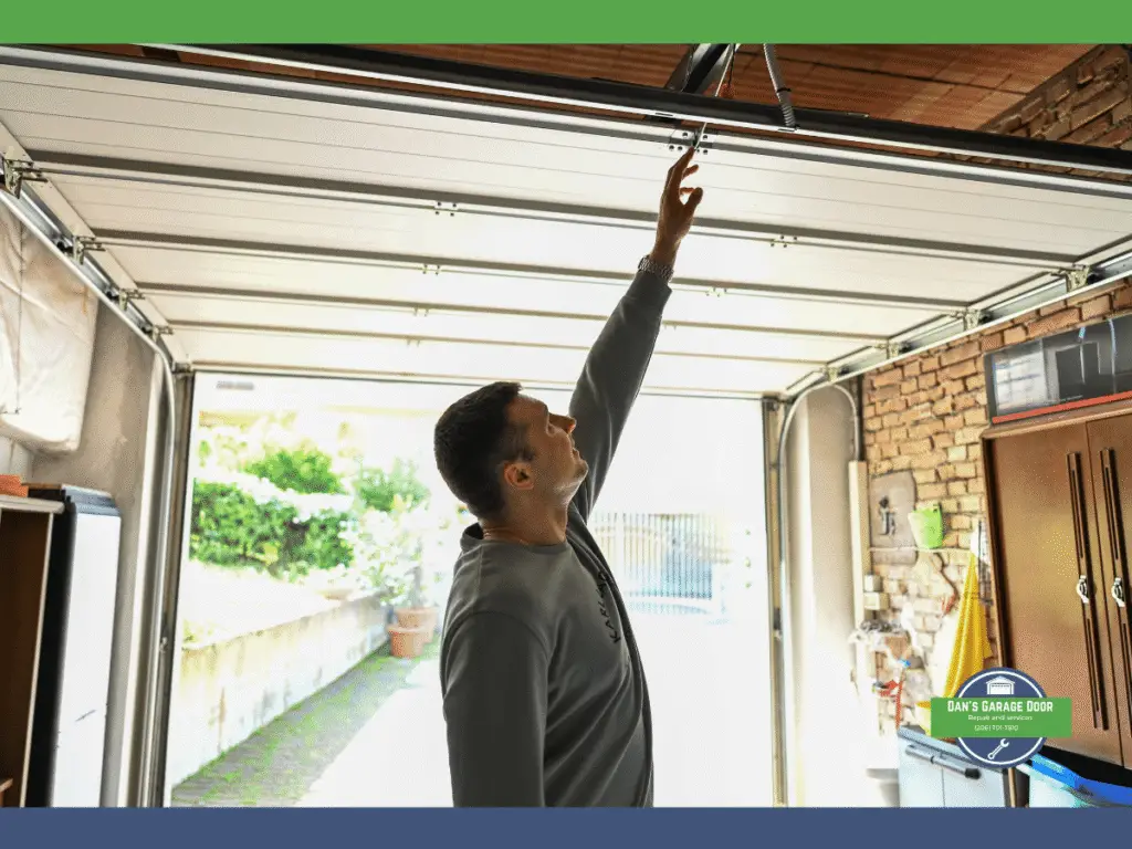 Man inspecting the mechanism of a garage door in a residential setting.