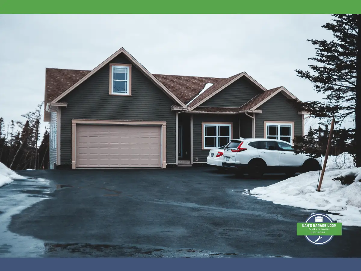 House with closed garage door, snowy driveway, and parked cars