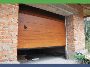Partially open wooden garage door in a brick wall, showing insulation materials inside.