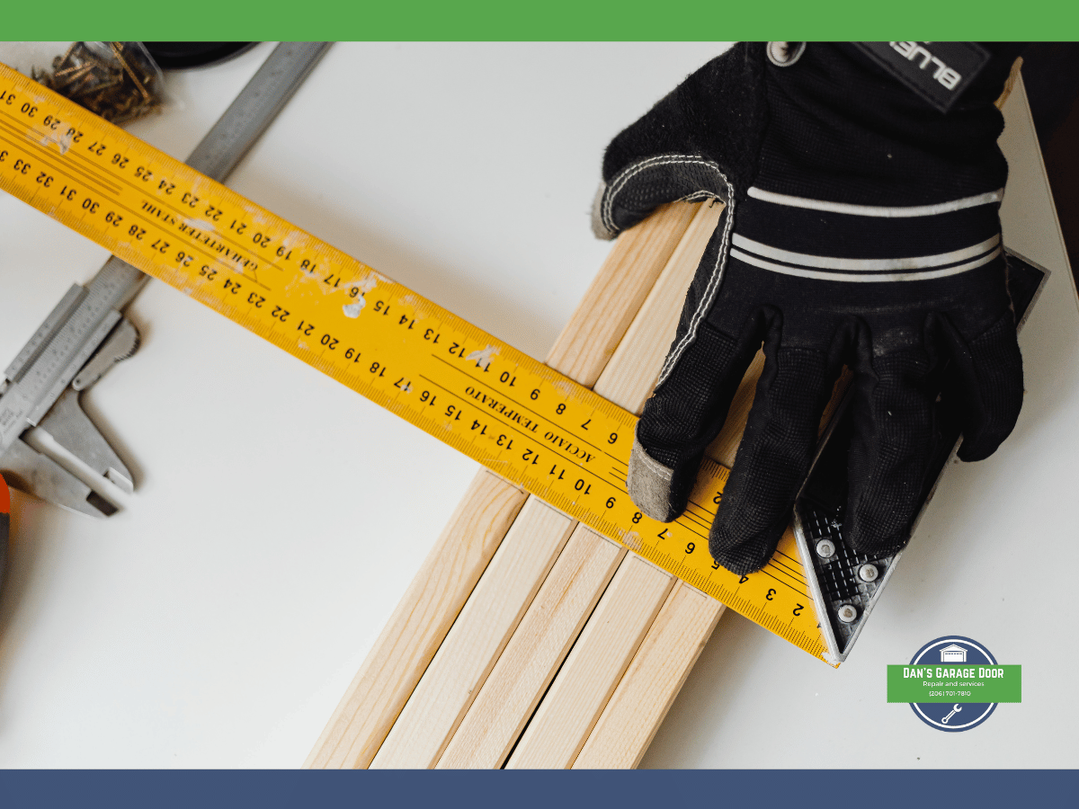 Measuring tape, caliper, and gloves on wooden planks for garage door sizing.