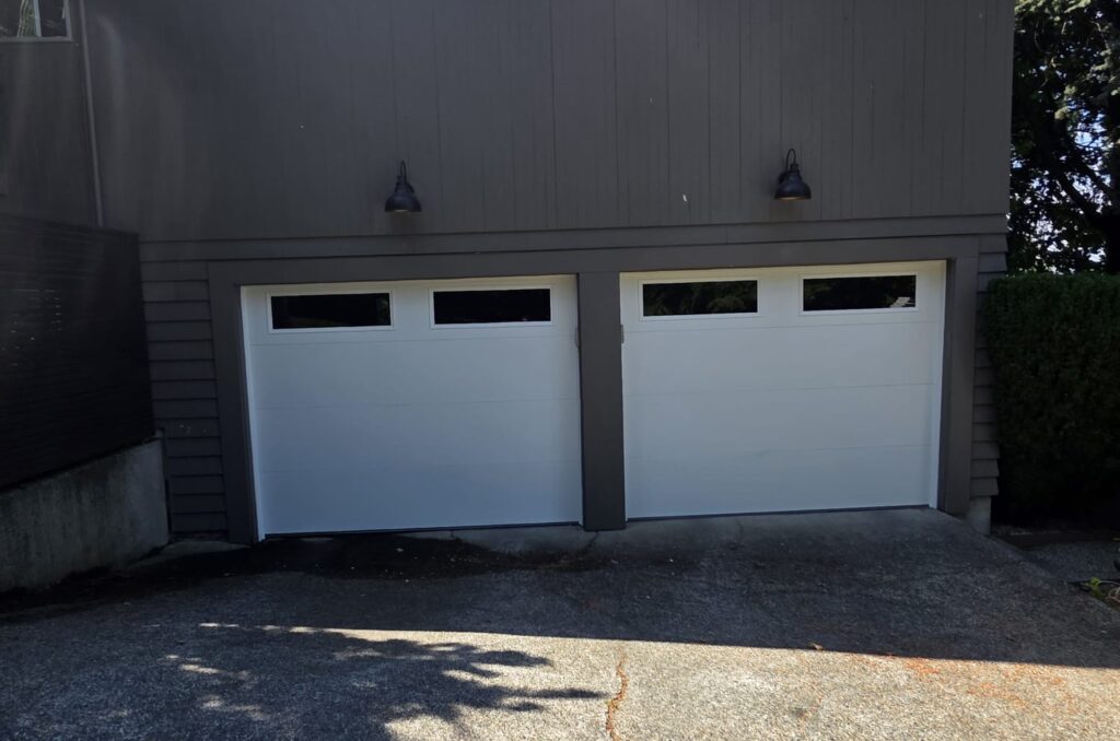 Two white garage doors on a dark house exterior