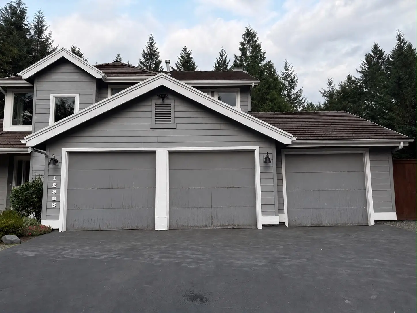 Gray house with three garage doors and water staining