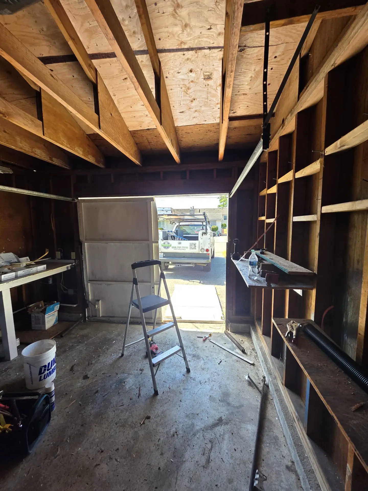 Construction inside a garage with open door and step ladder