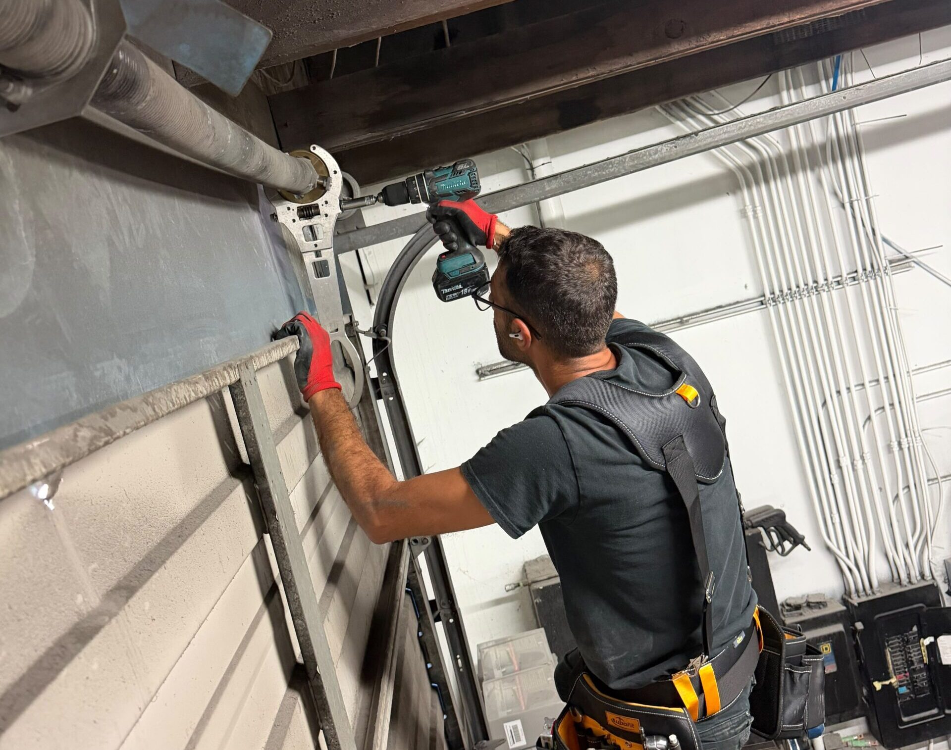 Technician using power drill on industrial overhead door mechanism