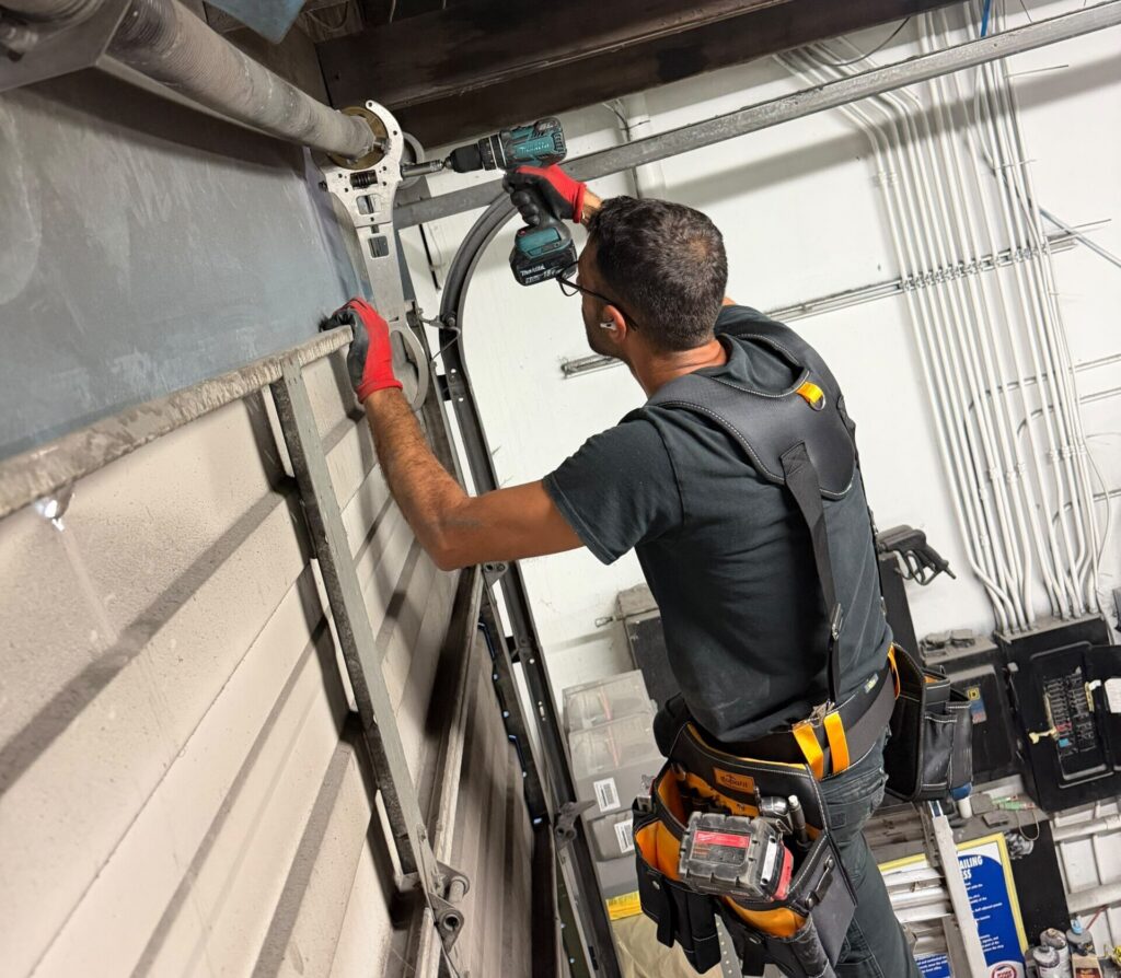 Technician uses a power drill on an overhead pipe bracket