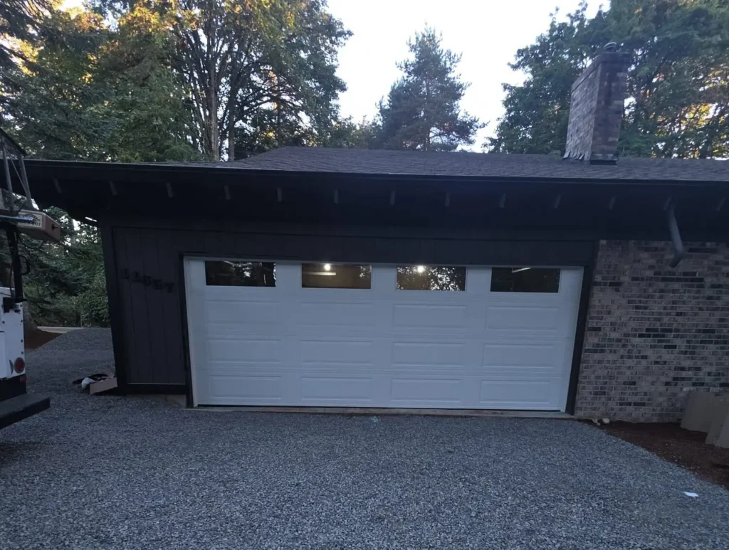 White garage door on dark house with gravel driveway