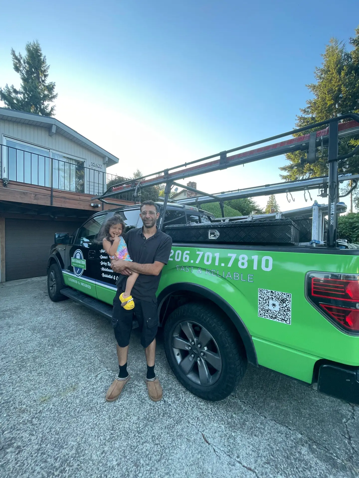 Man holding child beside green service truck