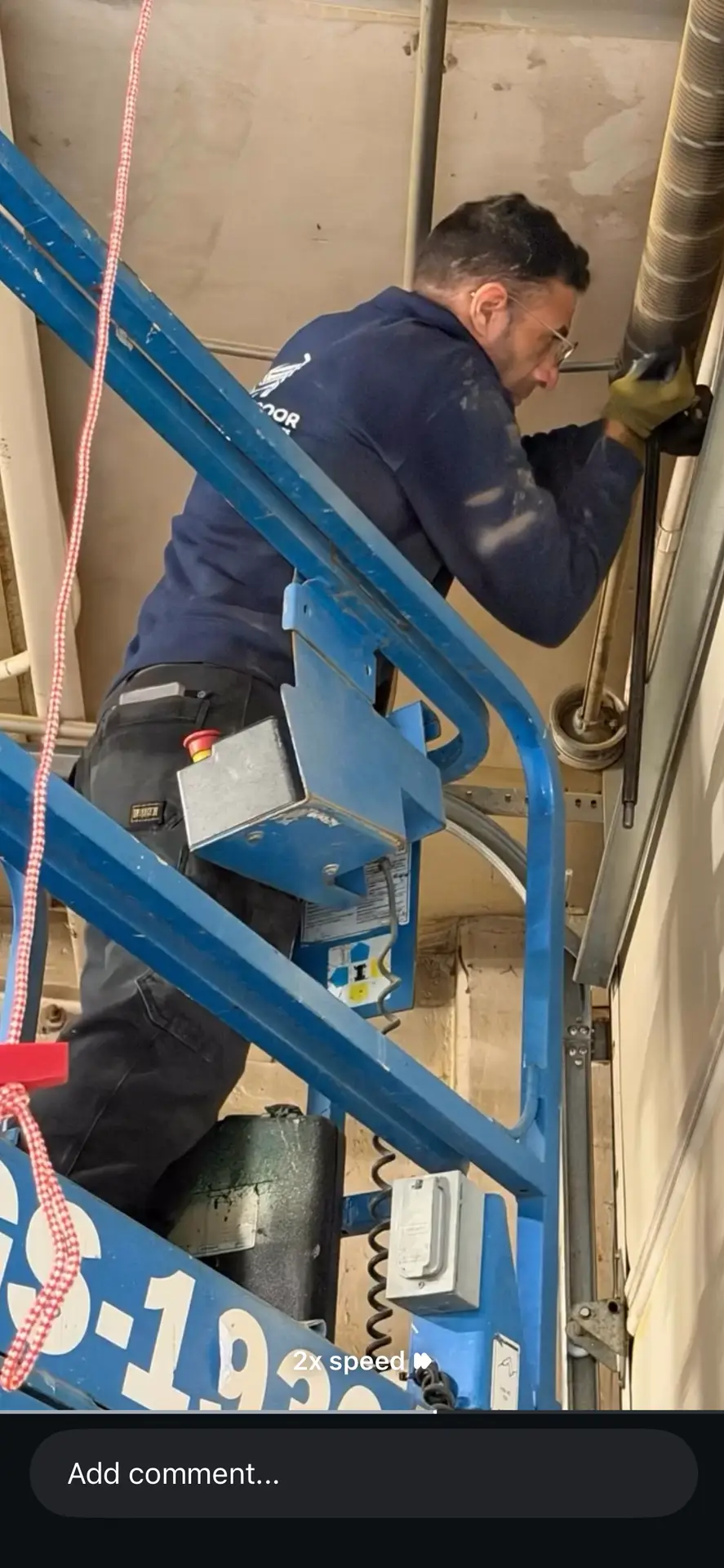Worker on blue lift adjusting overhead door hardware