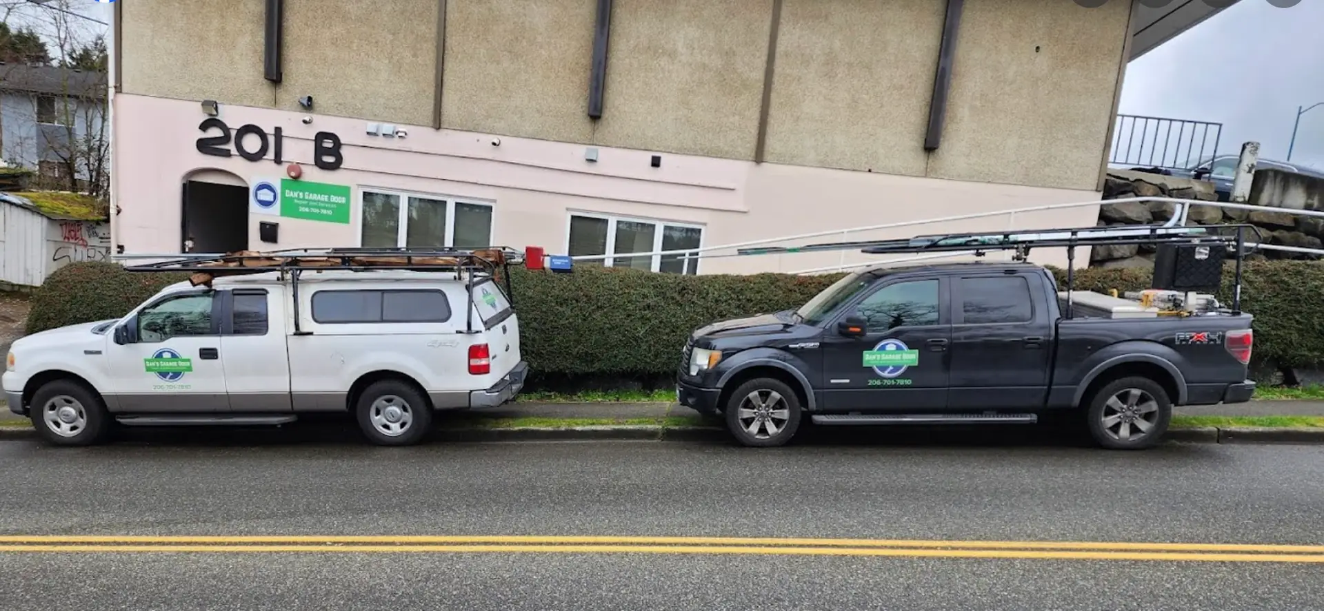 Two service pickup trucks parked outside a building, one white and one black