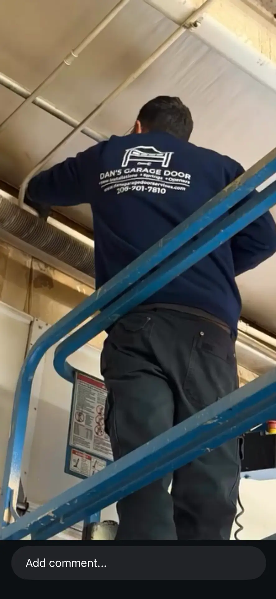 Technician on blue lift repairing garage door spring