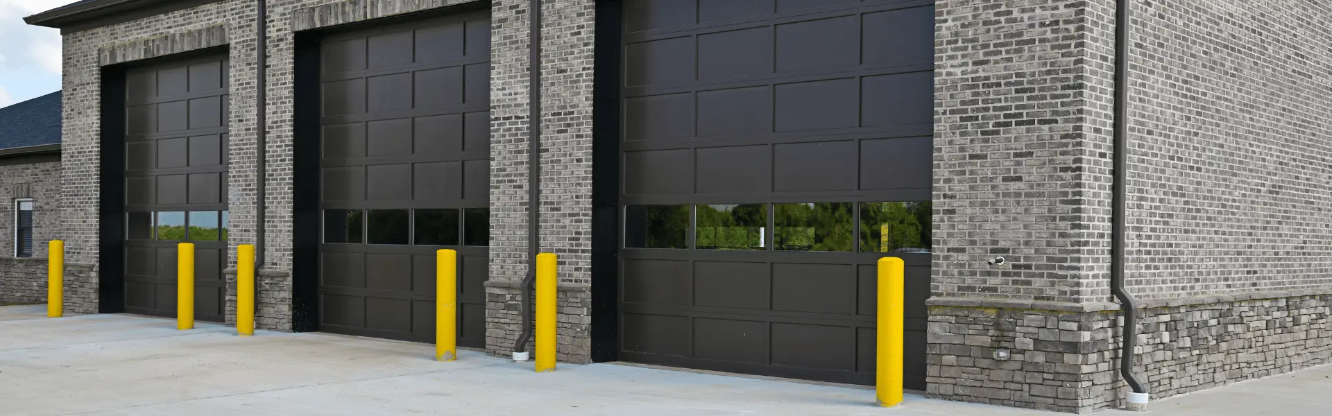 Three black commercial garage doors on brick building