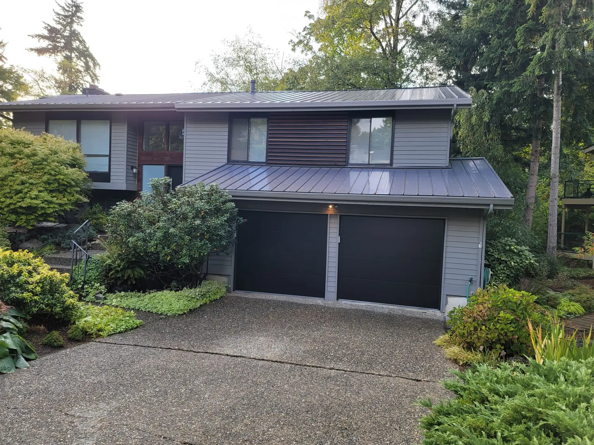 Gray modern two-story house with black double garage doors