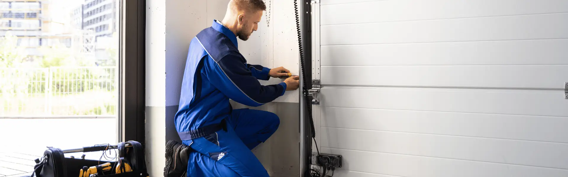 Technician in blue workwear repairing a garage door panel