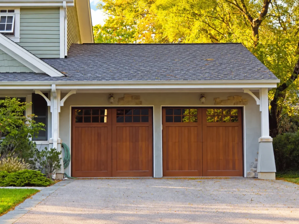 Two wooden garage doors on a house exterior