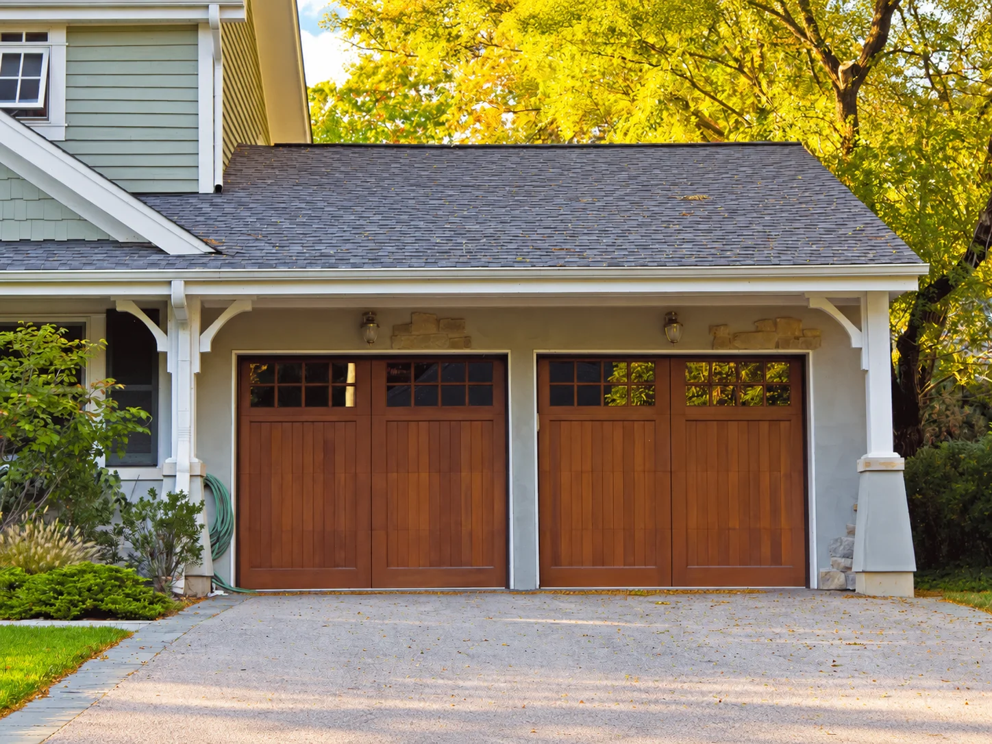 Two wooden garage doors on a house exterior