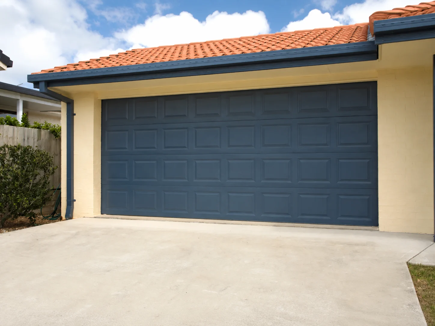 Blue paneled garage door on beige house exterior