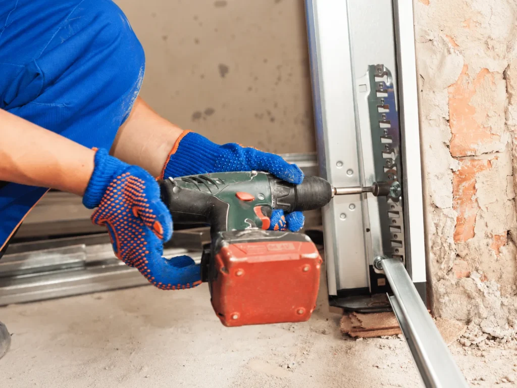 Worker drilling a garage door track with cordless drill
