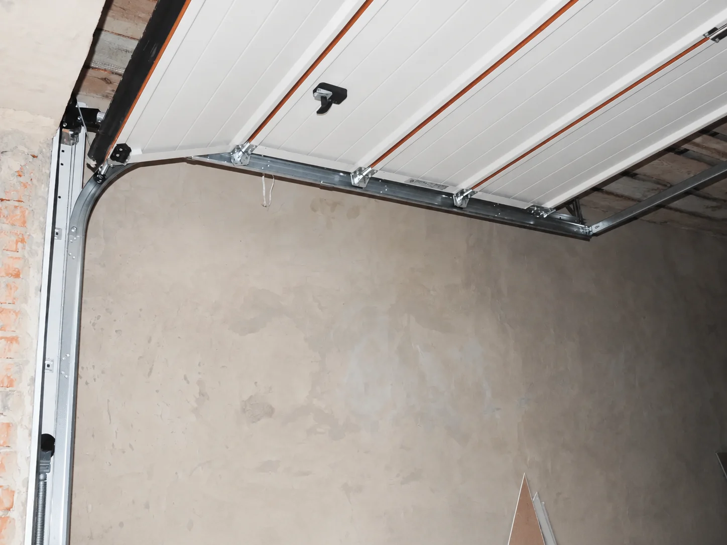 Partially open wooden garage door in brick opening
