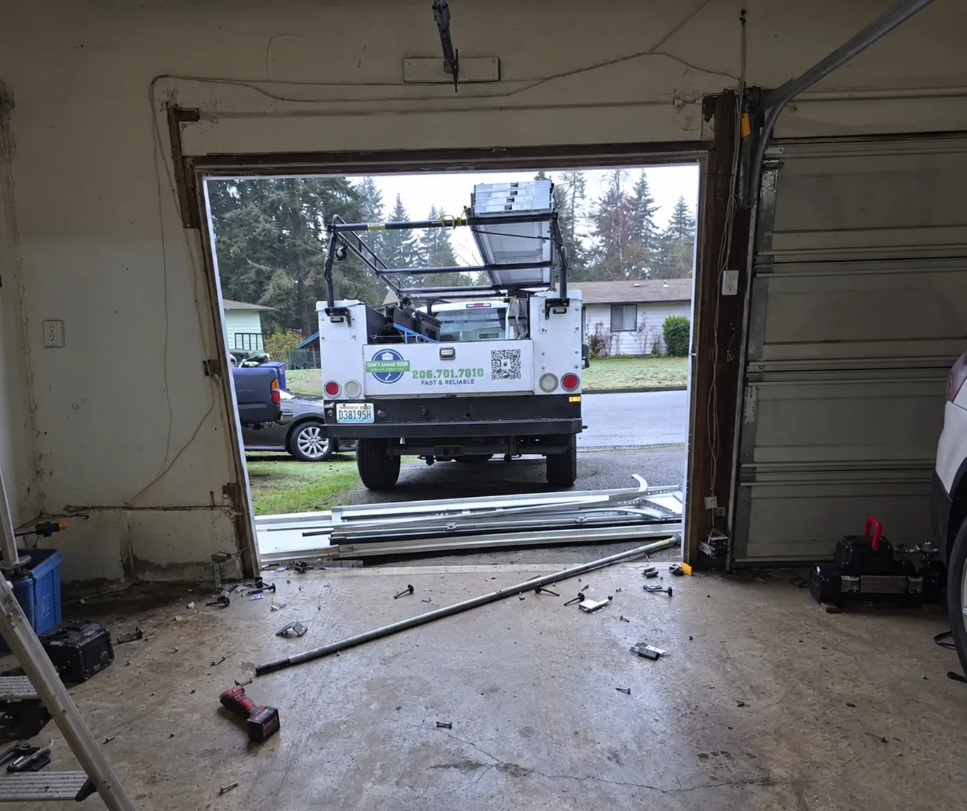 Garage doorway with work truck and door parts outside