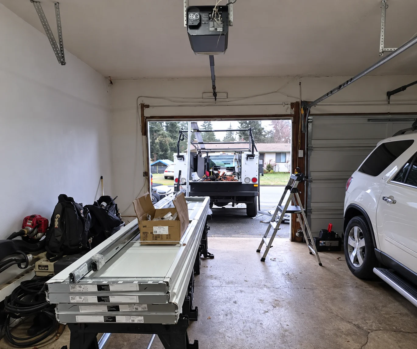 Garage interior with open door, work truck outside, and ladder