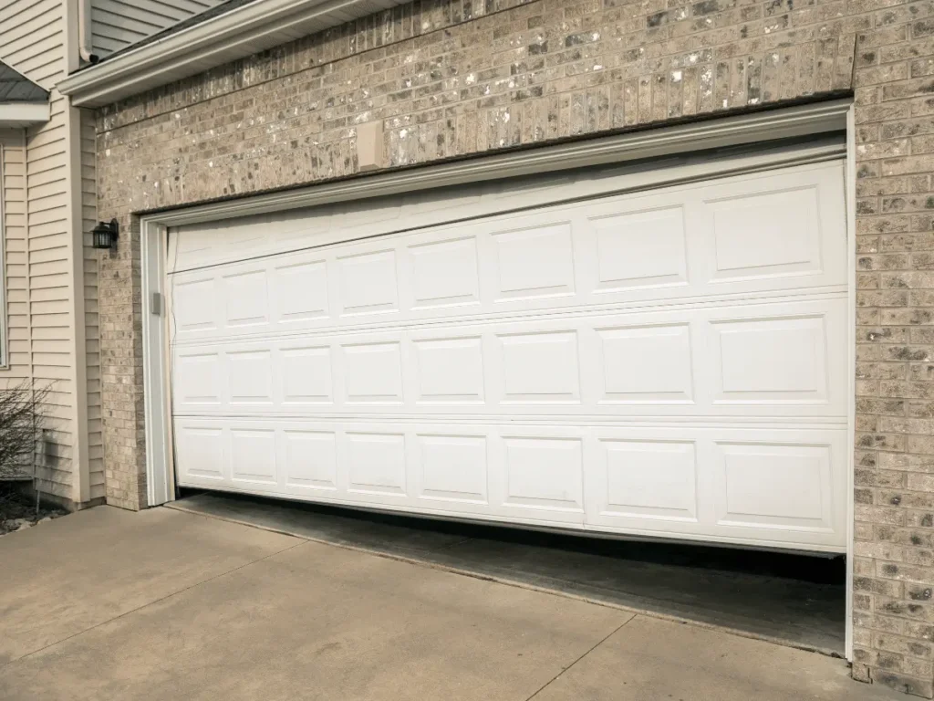 Partially open white garage door on brick house
