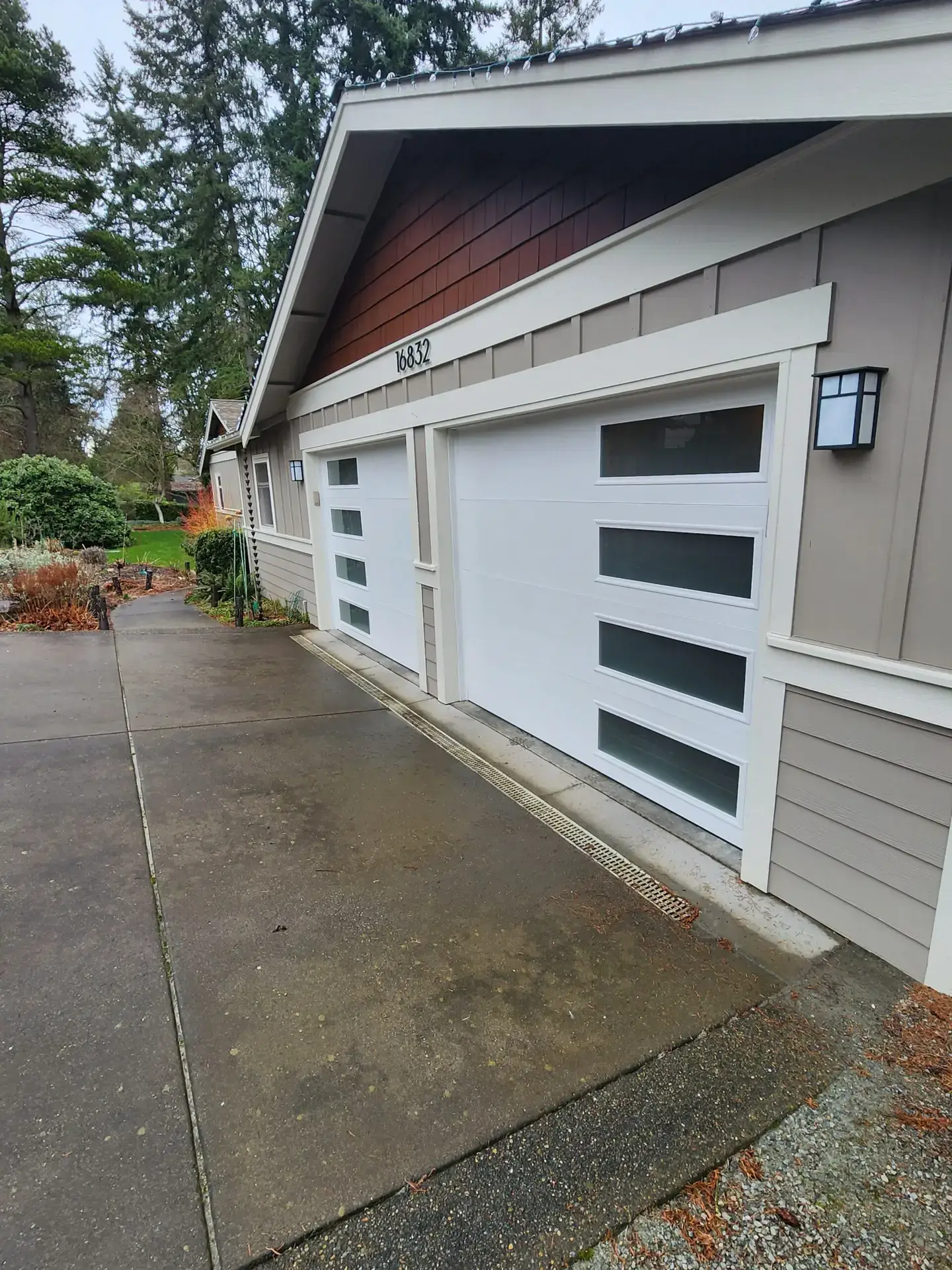 Two white garage doors beside a wet driveway